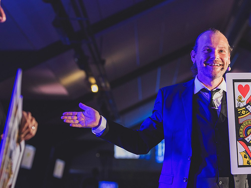 Anthony James révélant une grande carte lors d'un spectacle de scène